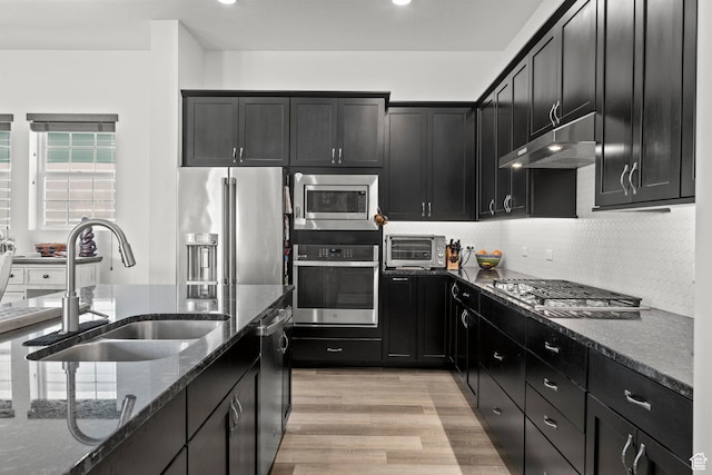 11242 S Willow Dr, South Jordan, UT 84009 - kitchen with appliances with stainless steel finishes, a sink, under cabinet range hood, dark stone countertops, and dark cabinetry