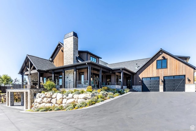900 W Weber Canyon Rd, Oakley, UT 84055 - view of front facade featuring a chimney, a garage, asphalt driveway, covered porch, and stone siding