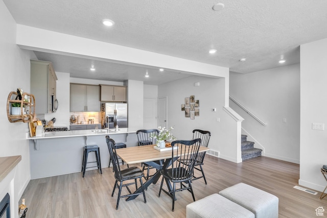 3791 W Soft Whisper Way, Herriman, UT 84096 - dining area featuring stairway, light wood-type flooring, recessed lighting, a textured ceiling, and baseboards