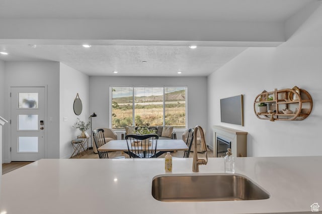 3791 W Soft Whisper Way, Herriman, UT 84096 - kitchen with a sink, wood finished floors, recessed lighting, light countertops, and a glass covered fireplace
