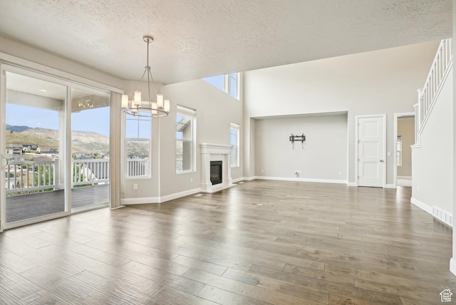 15056 S Sage Terrace Ln Unit 1014, Herriman, UT 84096 - unfurnished living room featuring a chandelier, wood-type flooring, a textured ceiling, baseboards, and a glass covered fireplace