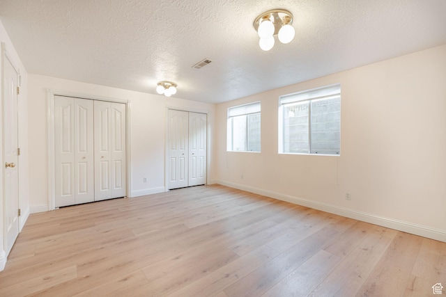 1055 E 900 S Unit 61, St George, UT 84790 - unfurnished bedroom featuring light wood-style floors, multiple closets, baseboards, and a textured ceiling