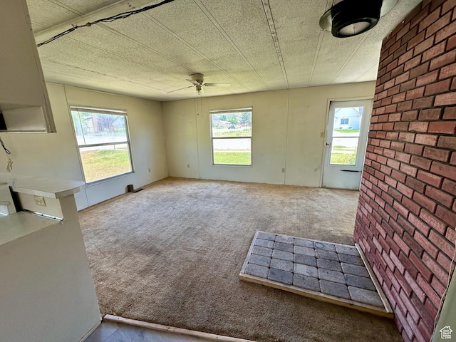 295 N 400 E, Nephi, UT 84648 - unfurnished living room with healthy amount of natural light, carpet flooring, ceiling fan, and brick wall