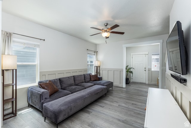 15187 S Sabre Pl, Bluffdale, UT 84065 - living room featuring a ceiling fan, light wood finished floors, a wainscoted wall, and a decorative wall