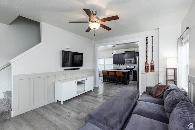15187 S Sabre Pl, Bluffdale, UT 84065 - living area with a ceiling fan, light wood-style floors, wainscoting, and stairway