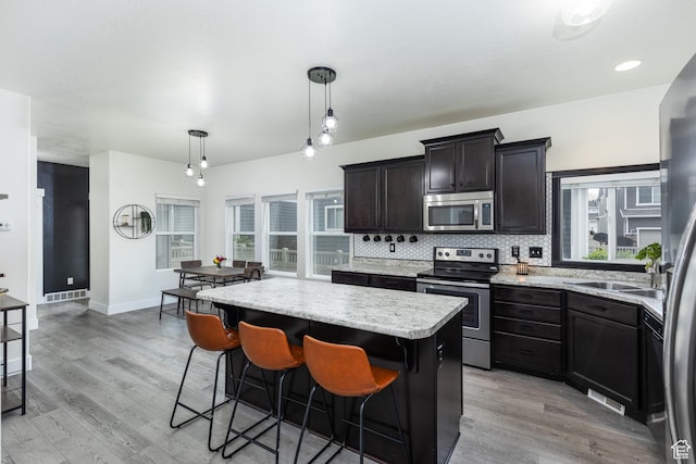 15187 S Sabre Pl, Bluffdale, UT 84065 - kitchen with appliances with stainless steel finishes, a center island, light wood-type flooring, and tasteful backsplash