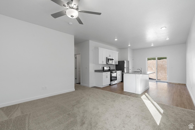 7164 Oquirrh Ranch Pkwy N, Eagle Mountain, UT 84005 - kitchen with stainless steel appliances, a sink, baseboards, a kitchen island with sink, and white cabinets