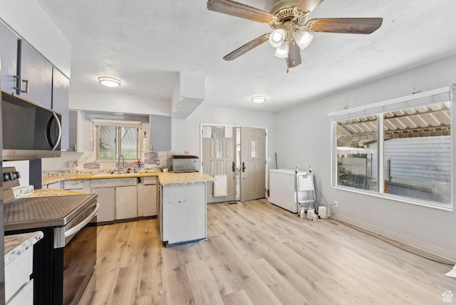 142 N Pinehurst Ave, Tooele, UT 84074 - kitchen featuring stainless steel microwave, electric range oven, a peninsula, light wood-type flooring, and a textured ceiling