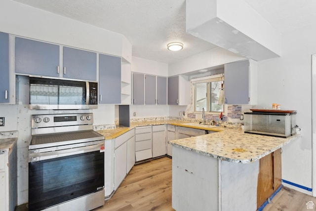 142 N Pinehurst Ave, Tooele, UT 84074 - kitchen with appliances with stainless steel finishes, a peninsula, a sink, light wood-style flooring, and open shelves