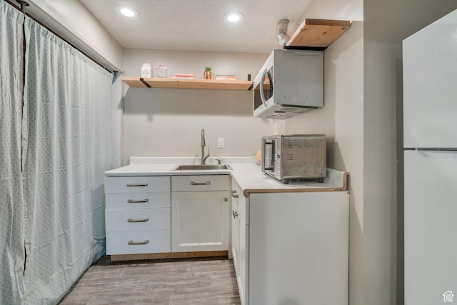 1460 E Lowe Peak Dr, Eagle Mountain, UT 84005 - kitchen with a sink, white appliances, light countertops, recessed lighting, and white cabinetry