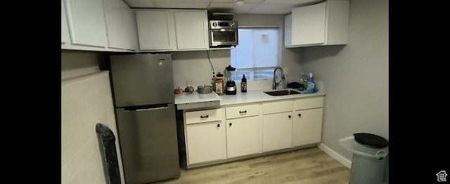 1004 N Sir Michael Dr, Salt Lake City, UT 84116 - kitchen featuring freestanding refrigerator, a sink, light countertops, light wood-style floors, and white cabinetry