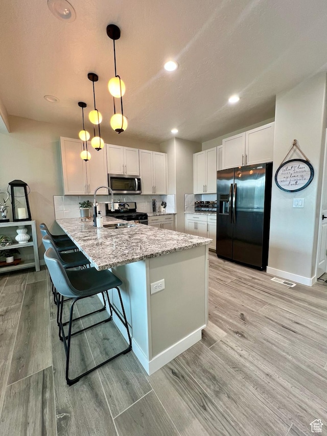 15456 S Navy Trails Ln W, Bluffdale, UT 84065 - kitchen with appliances with stainless steel finishes, a peninsula, a sink, light wood-style flooring, and white cabinets