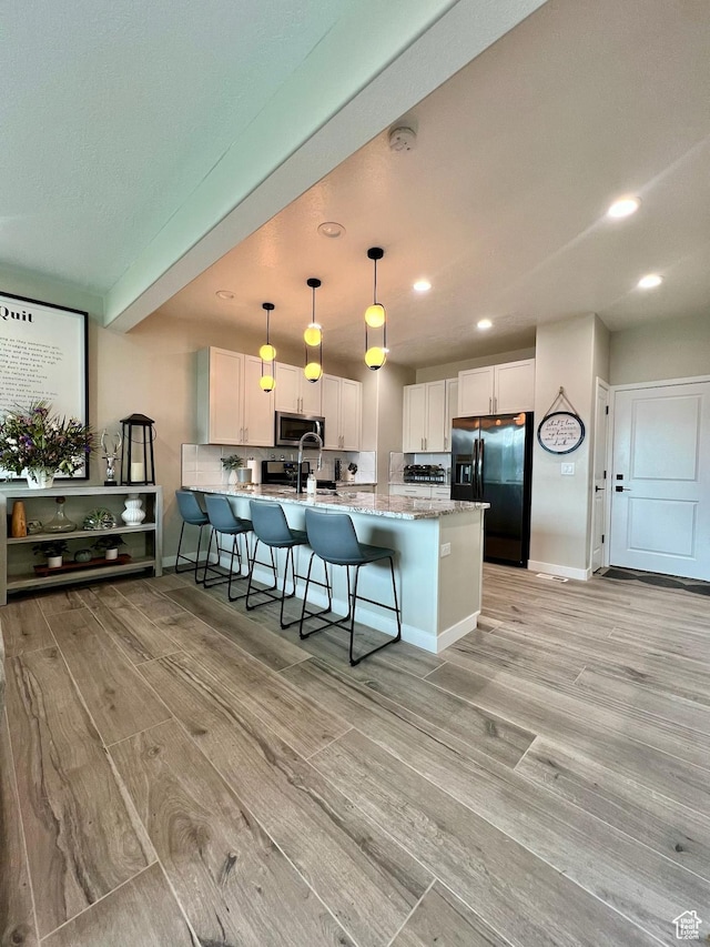 15456 S Navy Trails Ln W, Bluffdale, UT 84065 - kitchen featuring black fridge, light wood-style floors, a peninsula, white cabinets, and stainless steel microwave
