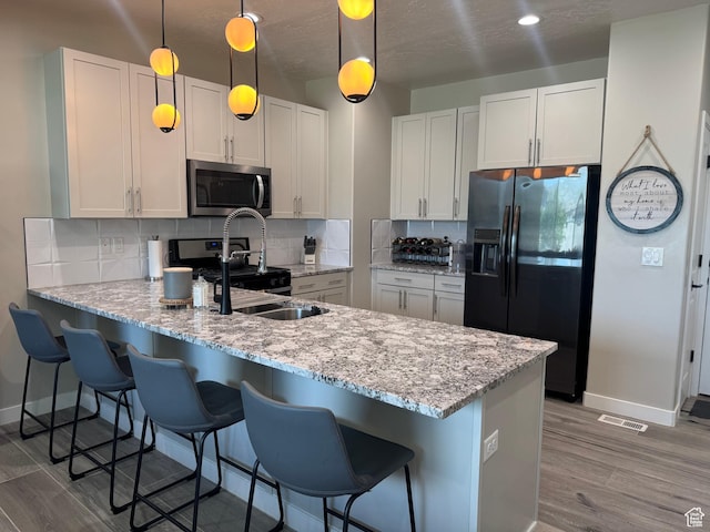 15456 S Navy Trails Ln W, Bluffdale, UT 84065 - kitchen with stainless steel microwave, black refrigerator with ice dispenser, baseboards, a peninsula, and tasteful backsplash