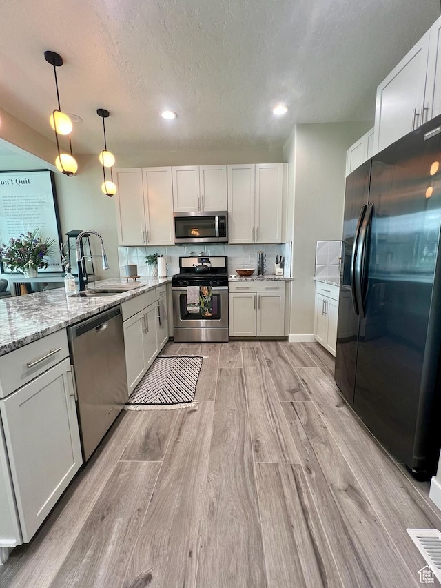 15456 S Navy Trails Ln W, Bluffdale, UT 84065 - kitchen featuring stainless steel appliances, a sink, light wood-style floors, light stone counters, and pendant lighting