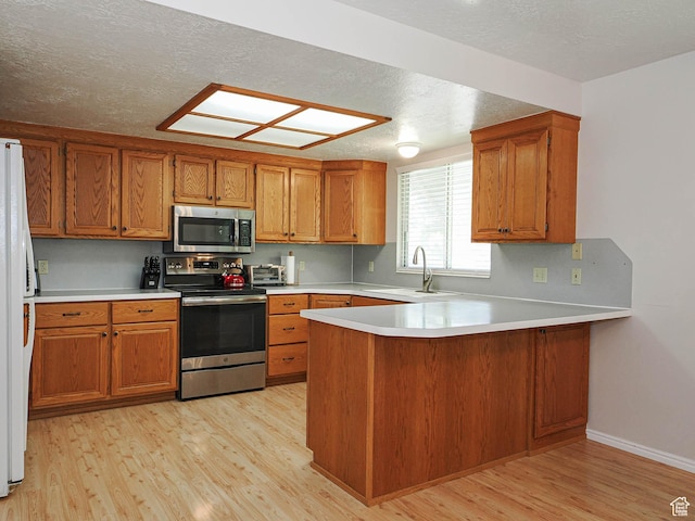 1090 E 2125 N, Layton, UT 84041 - kitchen with appliances with stainless steel finishes, a sink, a peninsula, light wood-style flooring, and brown cabinetry