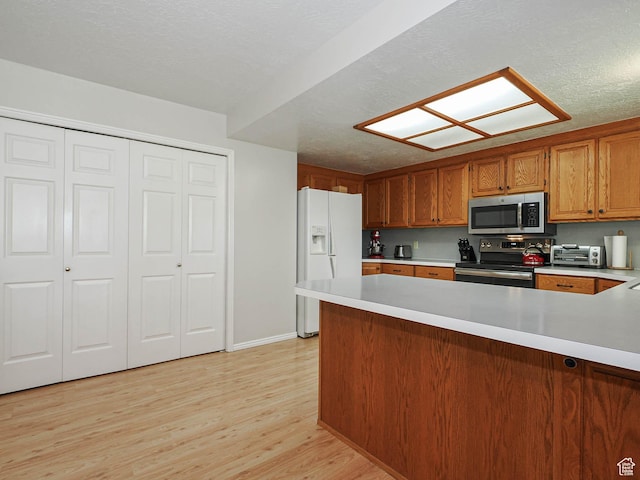 1090 E 2125 N, Layton, UT 84041 - kitchen with stainless steel appliances, light countertops, a peninsula, light wood finished floors, and brown cabinetry