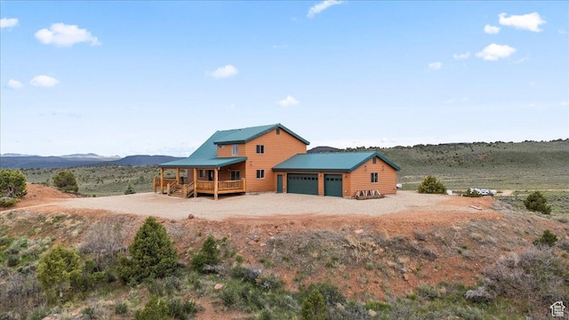 46982 W Thunder Ridge Rd, Fruitland, UT 84027 - back of house featuring a garage, log veneer siding, driveway, metal roof, and a mountain view