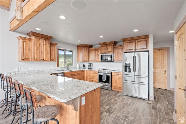 46982 W Thunder Ridge Rd, Fruitland, UT 84027 - kitchen featuring appliances with stainless steel finishes, a peninsula, recessed lighting, a sink, and light stone counters