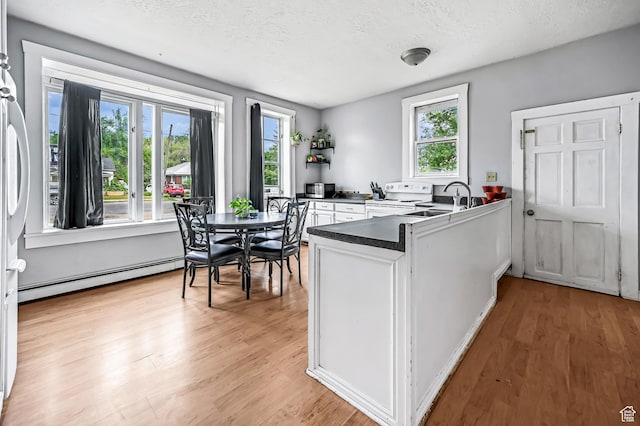 201 S 400 W, Logan, UT 84321 - kitchen featuring white range with electric stovetop, a peninsula, a baseboard heating unit, a textured ceiling, and white cabinets
