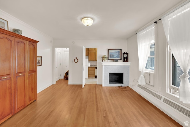 29 S State St Unit 810, Salt Lake City, UT 84111 - unfurnished living room featuring light wood-style floors, a tile fireplace, a baseboard radiator, baseboards, and crown molding