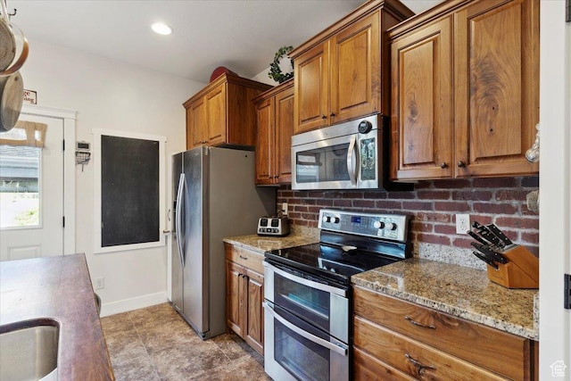 255 W 2700 N Unit 31, Pleasant View, UT 84414 - kitchen with stainless steel appliances, brown cabinets, light stone countertops, backsplash, and baseboards