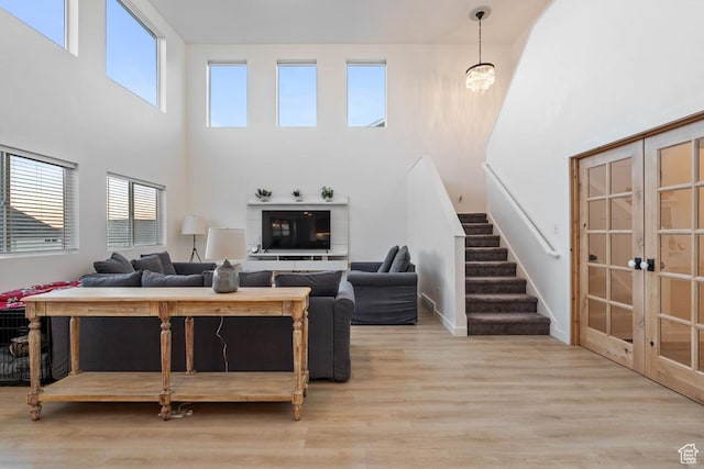 144 E Shorewood Dr S, Saratoga Springs, UT 84045 - living room featuring wood finished floors, a towering ceiling, stairway, french doors, and baseboards