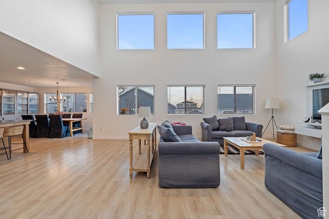144 E Shorewood Dr S, Saratoga Springs, UT 84045 - living room featuring a chandelier, a towering ceiling, light wood-style floors, plenty of natural light, and baseboards