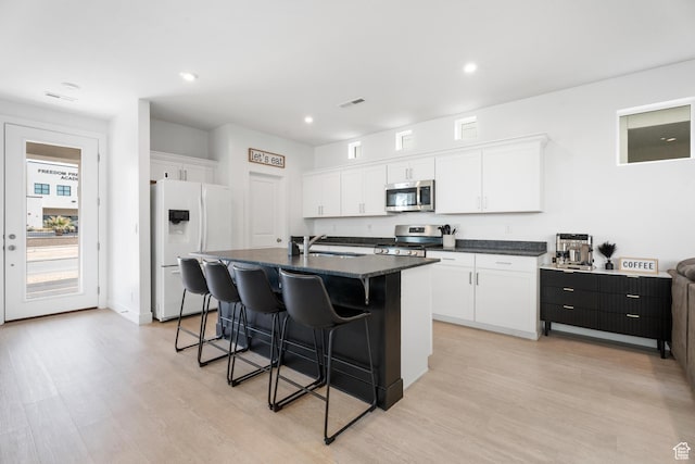 5670 S Carnelian Pkwy S, Bloomington, UT 84790 - kitchen featuring appliances with stainless steel finishes, a kitchen breakfast bar, light wood-style flooring, white cabinets, and a center island with sink