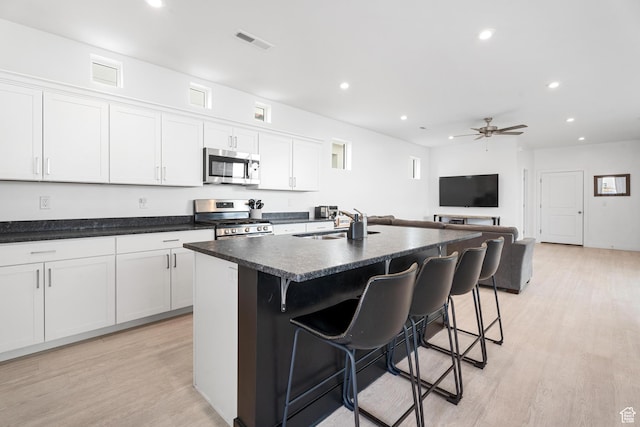 5670 S Carnelian Pkwy S, Bloomington, UT 84790 - kitchen with appliances with stainless steel finishes, light wood finished floors, a breakfast bar, a center island with sink, and recessed lighting