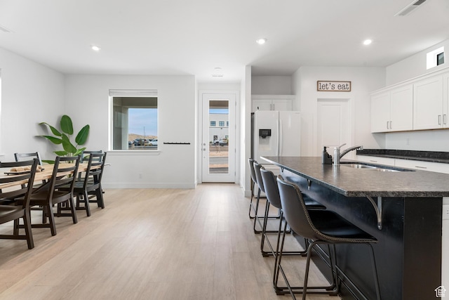 5670 S Carnelian Pkwy S, Bloomington, UT 84790 - kitchen with dark countertops, a sink, white fridge with ice dispenser, light wood finished floors, and a kitchen bar