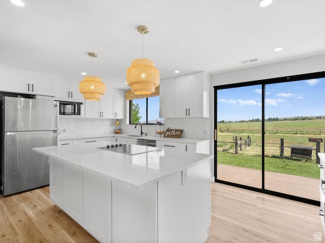 1491 Bryan Rd, Erda, UT 84074 - kitchen with appliances with stainless steel finishes, decorative backsplash, light wood finished floors, a center island, and recessed lighting