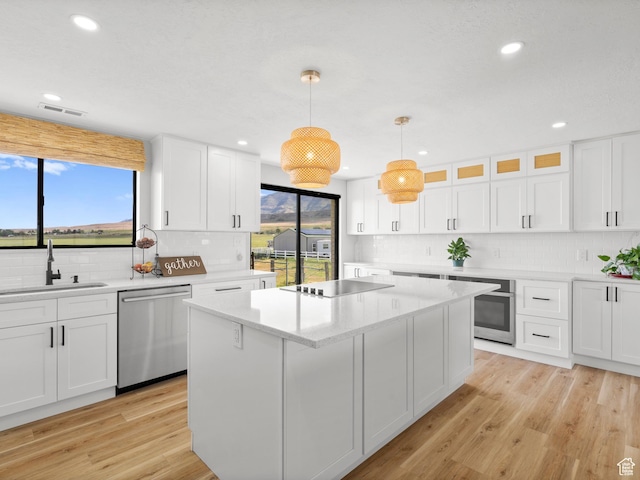 1491 Bryan Rd, Erda, UT 84074 - kitchen with appliances with stainless steel finishes, a sink, backsplash, white cabinets, and a center island