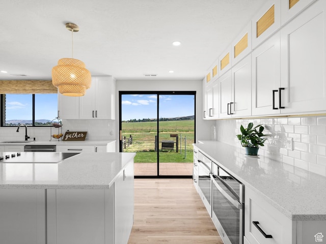 1491 Bryan Rd, Erda, UT 84074 - kitchen with a sink, backsplash, light wood-style floors, white cabinetry, and recessed lighting