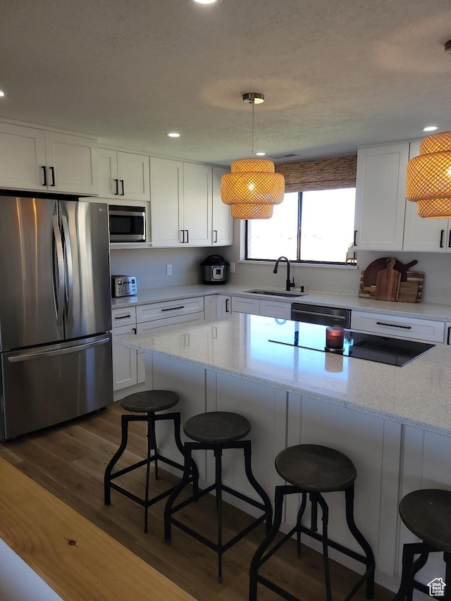 1491 Bryan Rd, Erda, UT 84074 - kitchen with stainless steel appliances, a sink, white cabinets, dark wood-style flooring, and a breakfast bar
