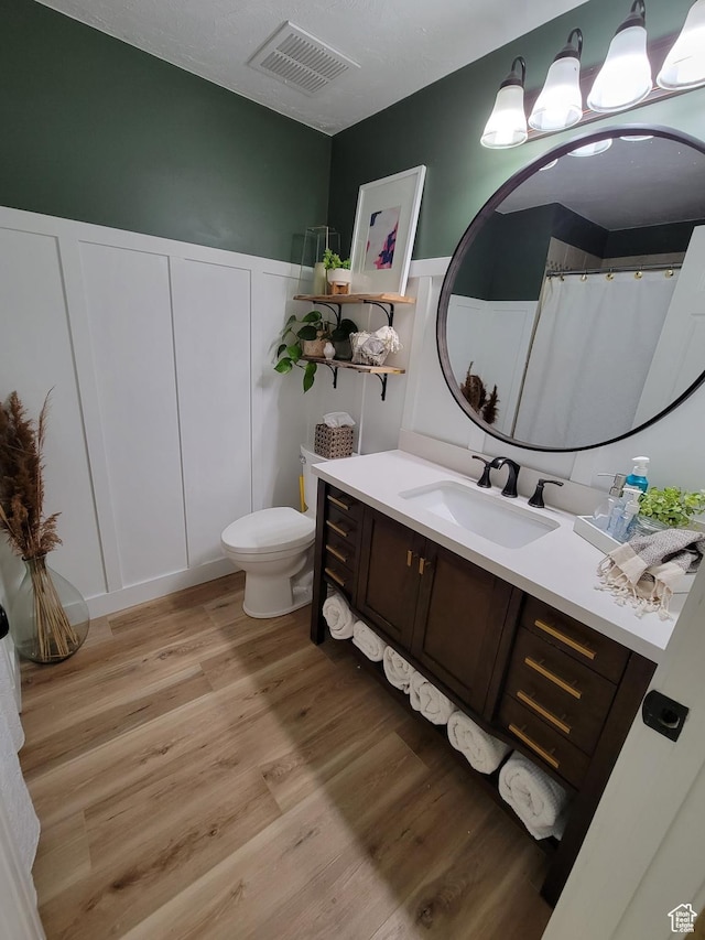 1491 Bryan Rd, Erda, UT 84074 - full bathroom featuring vanity, wood finished floors, toilet, and a decorative wall