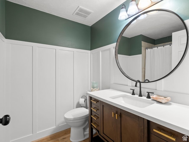 1491 Bryan Rd, Erda, UT 84074 - bathroom with wood finished floors, toilet, vanity, a decorative wall, and wainscoting