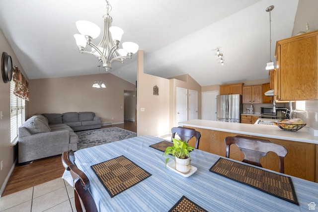 6216 S Waller Ln W, West Jordan, UT 84081 - dining area with vaulted ceiling, a chandelier, light tile patterned flooring, and baseboards