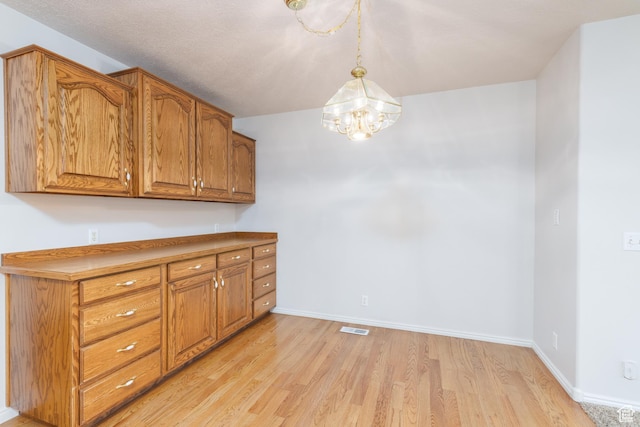 2275 W 1500 S Unit 28, Syracuse, UT 84075 - kitchen with brown cabinetry, light wood-style flooring, a chandelier, baseboards, and hanging light fixtures