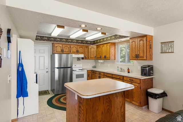 27 Lake W Cir, Fish Haven, ID 83287 - kitchen with freestanding refrigerator, white range with electric cooktop, a sink, brown cabinets, and under cabinet range hood
