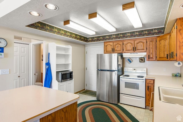 27 Lake W Cir, Fish Haven, ID 83287 - kitchen with stainless steel appliances, a sink, brown cabinets, light countertops, and a textured ceiling