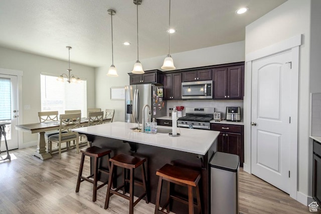 2068 N 3830 W, Lehi, UT 84043 - kitchen featuring stainless steel appliances, a breakfast bar, light countertops, light wood-type flooring, and recessed lighting