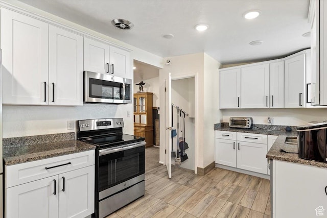5680 S 2600 W Unit 12, Roy, UT 84067 - kitchen with appliances with stainless steel finishes, white cabinetry, dark stone countertops, recessed lighting, and light wood-style flooring