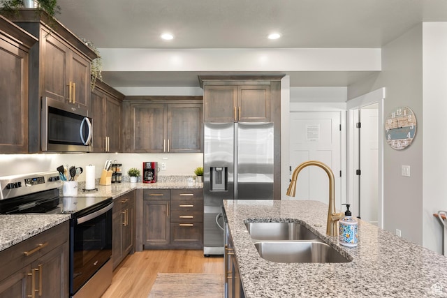 150 W Seasons Loop Unit 3, Garden City, UT 84028 - kitchen with stainless steel appliances, a sink, light wood finished floors, dark brown cabinetry, and light stone countertops