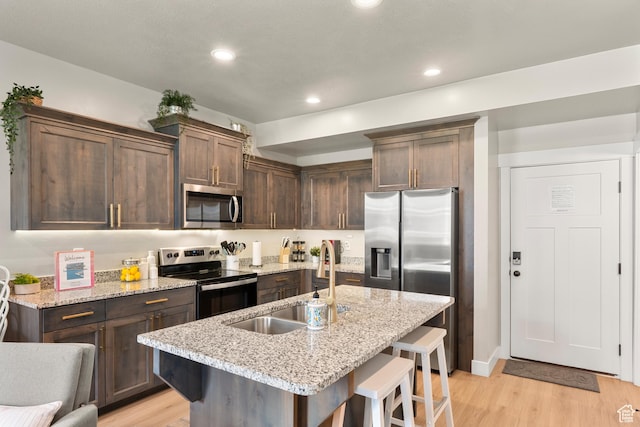 150 W Seasons Loop Unit 3, Garden City, UT 84028 - kitchen with stainless steel appliances, light wood-style floors, a sink, a kitchen breakfast bar, and dark brown cabinets