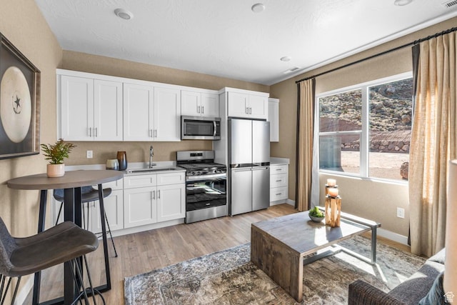 3719 E Padre Cv Unit 4092, Washington, UT 84780 - kitchen featuring appliances with stainless steel finishes, a sink, light wood-style flooring, white cabinetry, and baseboards