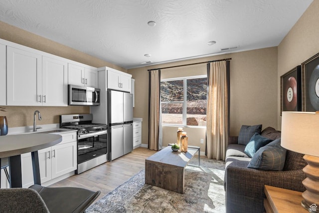 3719 E Padre Cv Unit 4092, Washington, UT 84780 - kitchen featuring stainless steel appliances, light wood-style flooring, white cabinets, and a sink