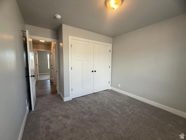 268 S 400 W, Tooele, UT 84074 - unfurnished bedroom featuring baseboards, dark carpet, a closet, and a textured ceiling