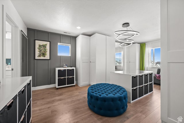 1067 W Ludington Ct, Bluffdale, UT 84065 - sitting room with a chandelier, light wood-style floors, a decorative wall, and a textured ceiling