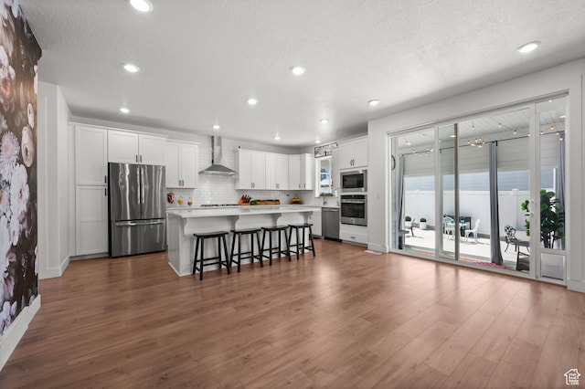 1067 W Ludington Ct, Bluffdale, UT 84065 - kitchen featuring appliances with stainless steel finishes, wall chimney range hood, a breakfast bar area, light countertops, and backsplash